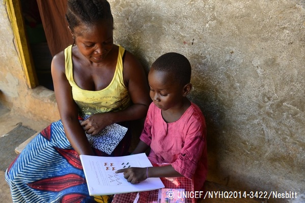 エボラ出血熱で学校が休校となっていた際、ユニセフはパートナー団体と協力して自宅で学習できるようにするための教材を配布。教材を使って母親と勉強をする男の子。© UNICEF_NYHQ2014-3422_Nesbitt