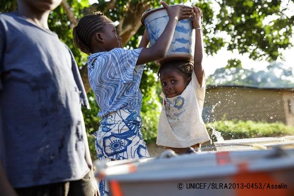 水でいっぱいになったバケツを頭に乗せる子ども。（シエラレオネ）© UNICEF_SLRA2013-0453_Asselin