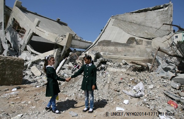 紛争で破壊されたガザ地区にある学校の前で友達と手をつなぐ10歳の少女。© UNICEF_NYHQ2014-1771_El Baba