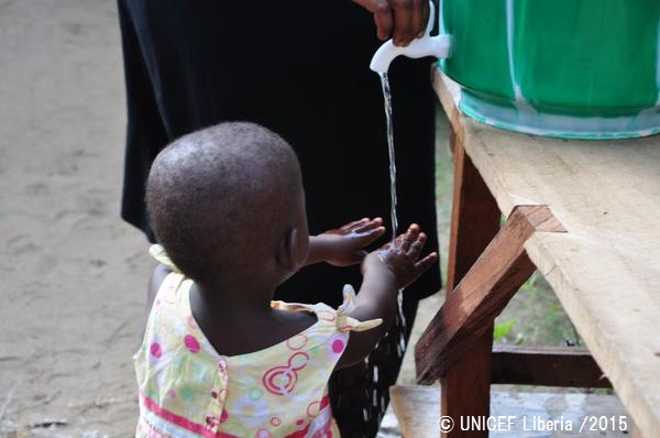消毒用の塩素が入った水で手を洗う女の子。© UNICEF Liberia_2015