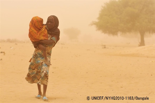 砂煙の中、幼い妹を抱えて歩く女の子。（チャド、2010年撮影）© UNICEF_NYHQ2010-1163_Gangale