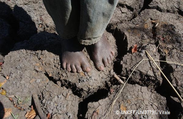 干ばつでひび割れた土の上に立つ男の子（マラウイ、2002年撮影）。© UNICEF_UNI37736_Vitale