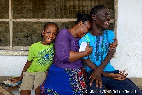 経過観察のための一時ケアセンターから出てきた子どもたちを抱きしめる、子どもたちの母親の友人。エボラで母親を失い、父親も何年も前に亡くなっているため、現在この女性の元で暮らしている（2014年11月撮影）。© UNICEF_UNI175185_Nesbitt