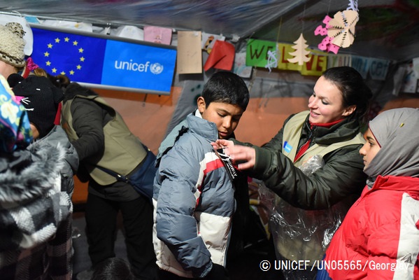 ユニセフの「子どもにやさしい空間」で新しく受け取った上着を着せてもらう男の子。（マケドニア）© UNICEF_UN05565_Georgiev