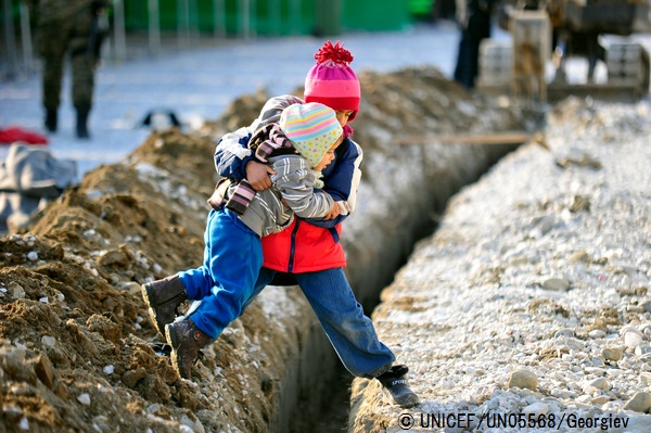 幼い妹が溝を乗り越えられるよう、抱っこして助けてあげる男の子。（マケドニア旧ユーゴスラビア共和国）© UNICEF_UN05568_Georgiev