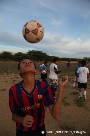 ユニセフのロゴが入ったFCバルセロナのユニフォームを着てサッカーをする男の子。© UNICEF_UNI119869_LeMoyne