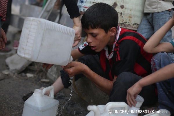 給水タンクから水を飲む、家族のために水を汲みに来た少年。（2014年撮影）© UNICEF_UNI168531_Khabieh