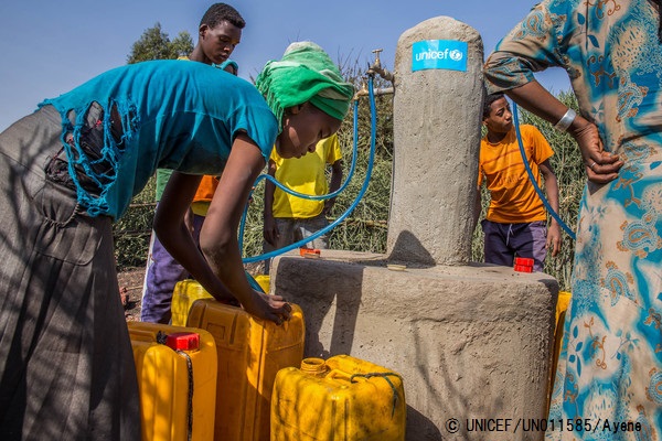 ユニセフが設置支援した給水所でタンクに水を汲む女性。© UNICEF_UN011585_Ayene