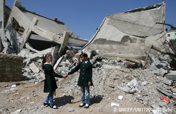 破壊された学校の前で、手をつなぐ10歳の女の子。（ガザ地区）© UNICEF_UNI172070_El Baba