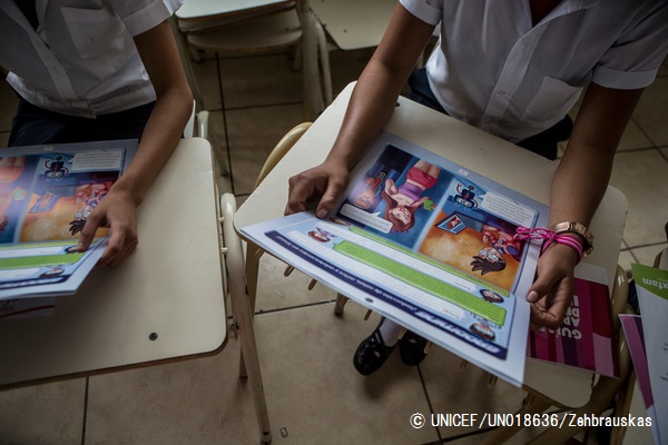 インターネット上のリスクや性的搾取から身を守るための啓発資料を読む子どもたち。（エルサルバドル）© UNICEF_UN018636_Zehbrauskas
