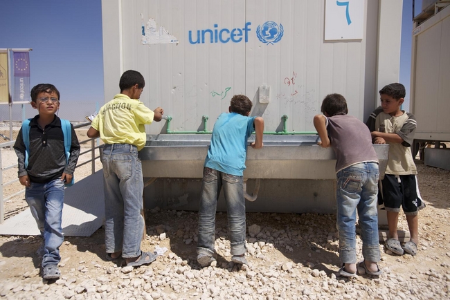 難民キャンプに設立された仮設校舎の裏で水を飲む男の子たち　(c)UNICEF/syria/2013/halabi