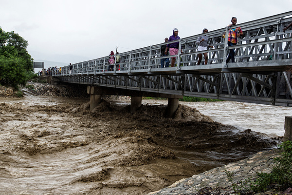 ハリケーン・マシュー通過後に、橋の上から水量が増した川を見る人々。（ポルトープランス　2016年10月4日撮影）© UNICEF_UN034482_Abassi, UN-MINUSTAH