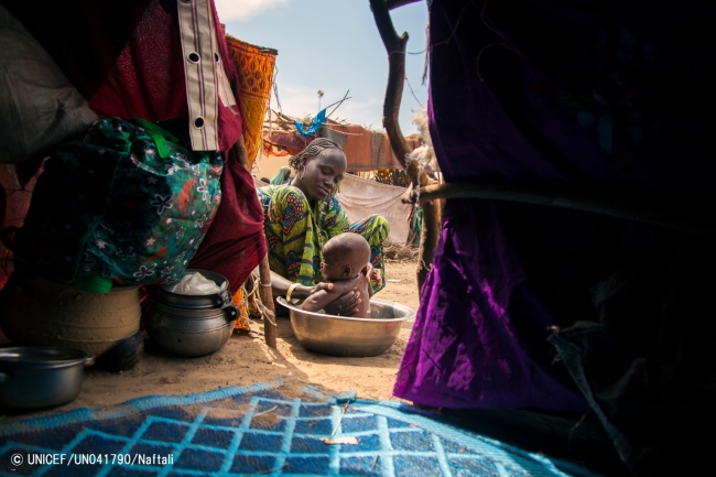 ナイジェリア・ボルノ州の国内避難民キャンプで子供を洗う女性。（2016年11月9日撮影）