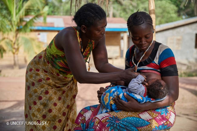 生後3カ月の息子に授乳する母親のカマラさん（写真右）。カマラさんの母親（写真左）が、寄り添って手助けをしている。（シエラレオネ）© UNICEF_UN065254_