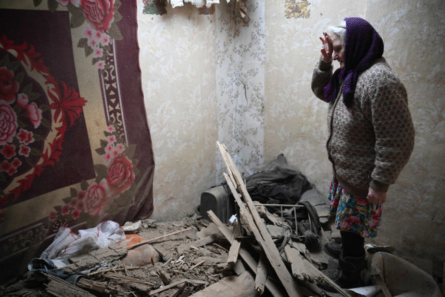 2022年２月24日、ドネツク地方。砲撃されて損傷した集合住宅の内部を案内する女性　(C)SNA