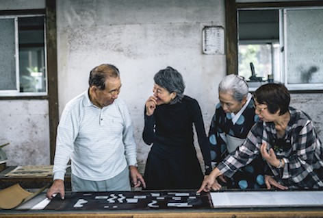 左は捺染職⼈の⽯井広実⽒。捺染台に張られた経⽷にこれ から型を⽤いて図柄を染めていく。Photo Kosuke Tamura