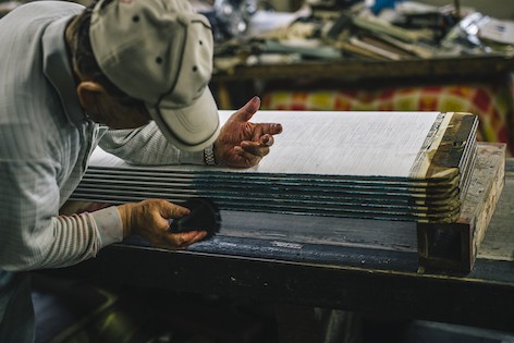 反物の幅に巻き取られた緯⽷は端に牡丹刷⽑で印をつける。 後の織りの⼯程での⽬印となる。Photo Kosuke Tamura