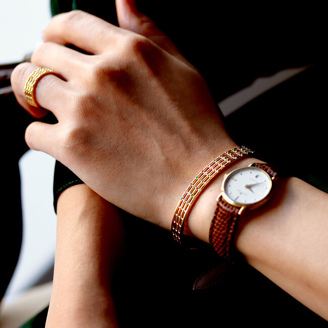 チェーン留めのバングルは女性らしい華奢な要素も。 チェーン留めのバングルは女性らしい華奢な要素も。