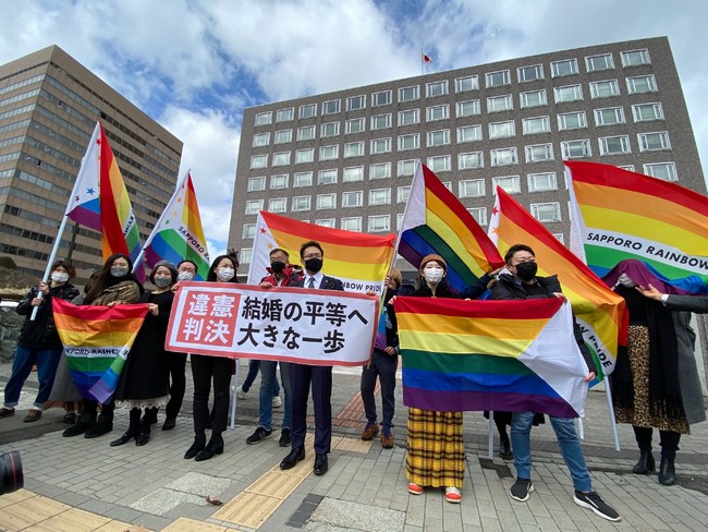 判決横断幕とレインボーフラッグを掲げる札幌の弁護団と支援者たち