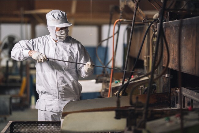 冨士屋製菓本舗の豆菓子を作る際のガスの直火で生地を付けた豆に火を入れえる「煎り」 冨士屋製菓本舗の豆菓子を作る際のガスの直火で生地を付けた豆に火を入れえる「煎り」
