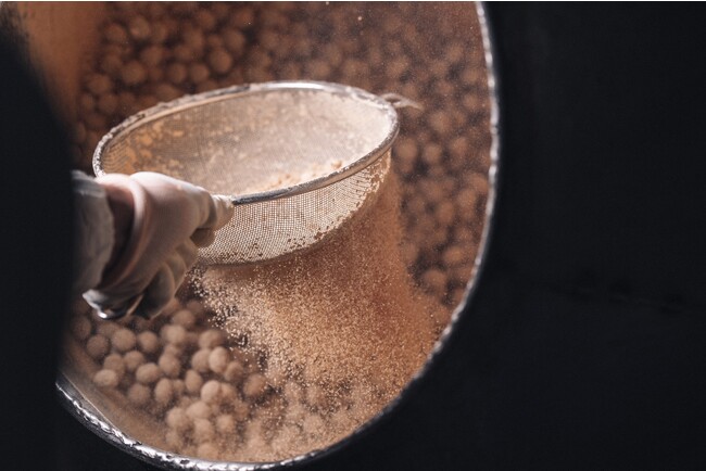 冨士屋製菓本舗の豆菓子を作る際の味付けできな粉をかける様子 冨士屋製菓本舗の豆菓子を作る際の味付けできな粉をかける様子