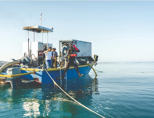 小さな船で出航し、ホースを持ったダイバーが海底へ潜る様子。 小さな船で出航し、ホースを持ったダイバーが海底へ潜る様子。