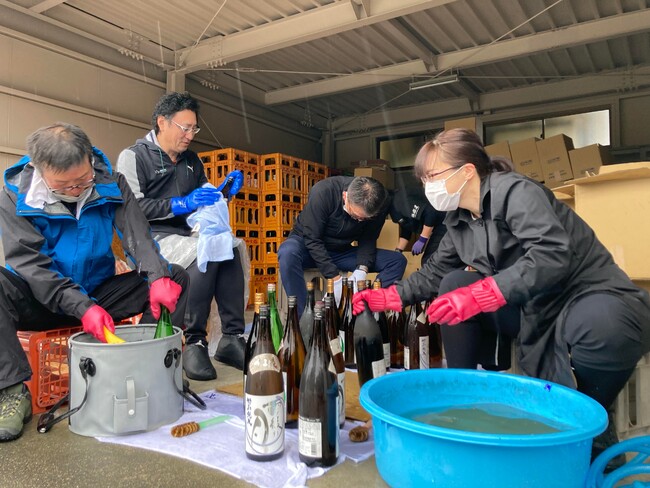 焼け跡から救い出した日本酒をボランティアの方々と洗浄