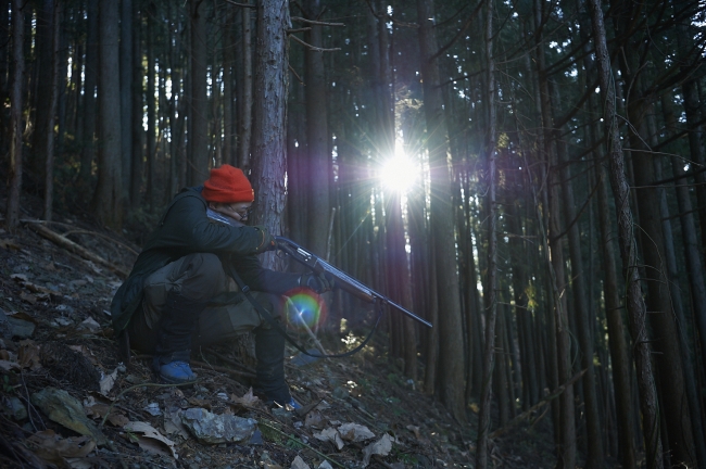 東京の森の中で息をひそめ、イノシシの出現を待つハンター