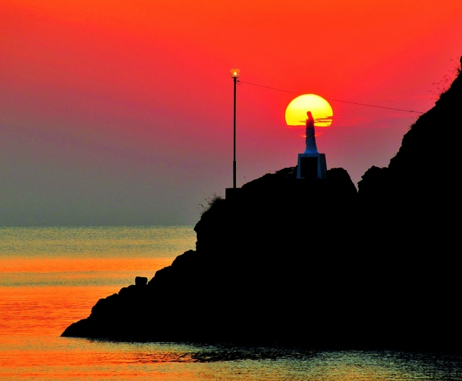 夕日の海に祈るマリア像（イメージ）