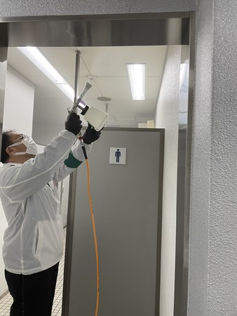 光触媒J-チタンHiKARiを男子トイレ天井に噴霧する様子　　  仙台市若林区役所