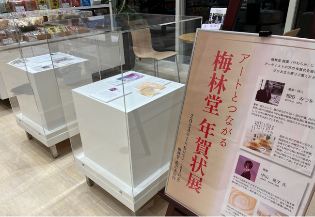 「アートとつながる梅林堂年賀状展」を箱田本店にて開催中。相田みつを氏が書かれた辰年の年賀状 (複製) や、画家 中山晃子氏作品。また熊谷ゆかりの書家51人による年賀状を展示。