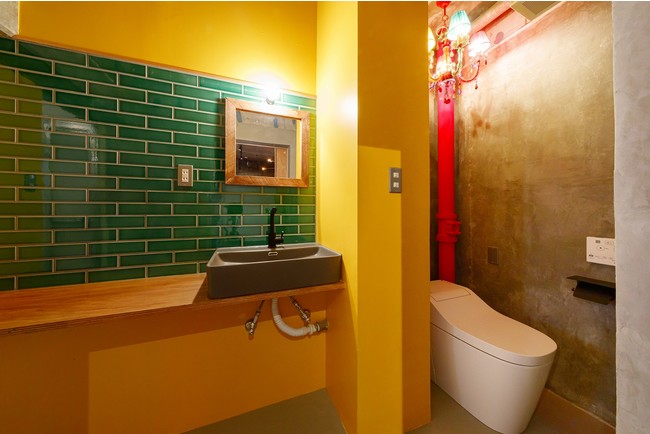 黄色の壁に緑のレンガがマッチした洗面所