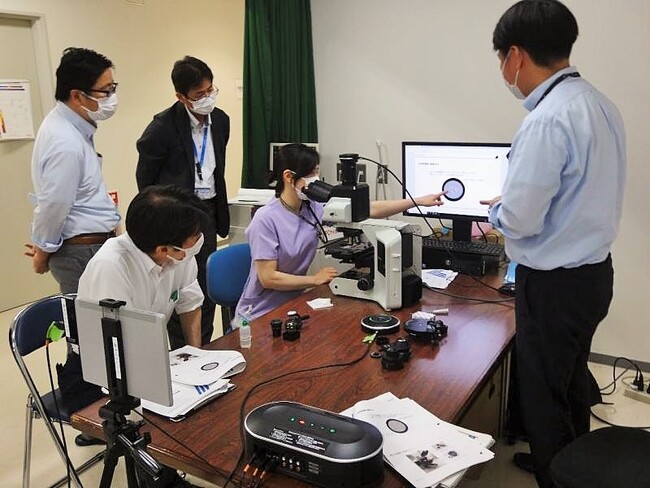 光学顕微鏡の位相差観察実技実習を受ける参加者ら