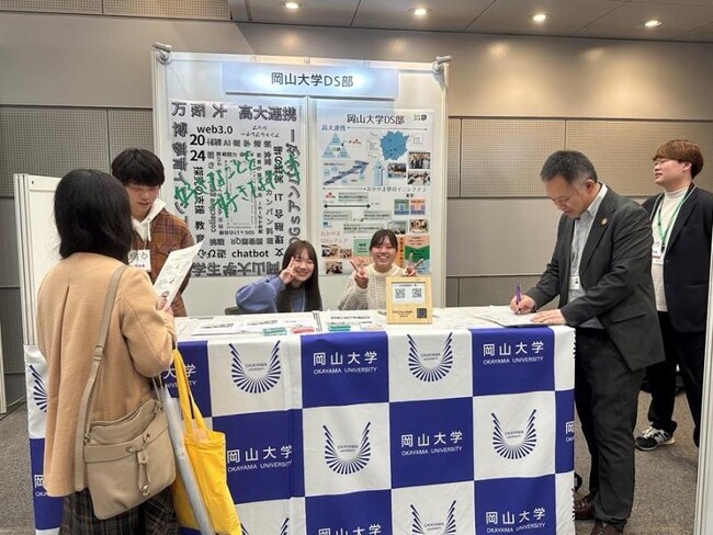 岡山大学データサイエンス部の展示ブースと顧問の野上副理事（右から2人目）