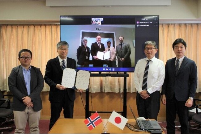 協定書を掲げる高瀬学部長（左から2人目）とMorten Ørbecck学部長（中央画面、左から2人目）