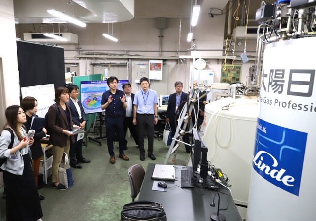 本学のヘリウム供給について説明する笠原教授（左から5人目）