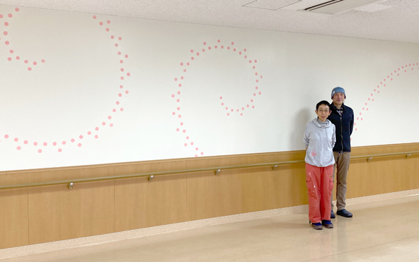 完成したデザインをバックに西山美なコさんと林伸光さん 完成したデザインをバックに西山美なコさんと林伸光さん