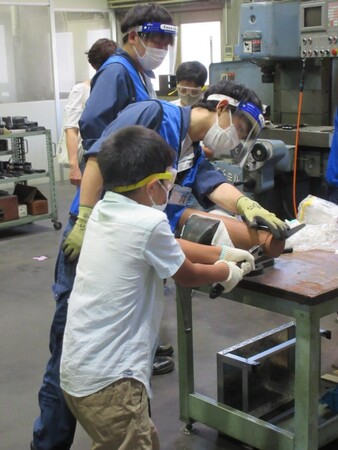 ノコギリを使い、丸太からコースター用の木材を切り分けている様子 ノコギリを使い、丸太からコースター用の木材を切り分けている様子