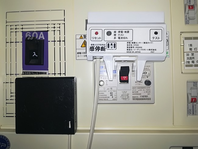 「感停断」本体を分電盤ブレーカ上部に両面接着テープで取付けます。左下は分電盤内部に両面接着テープで取付けた電池ボックスです。