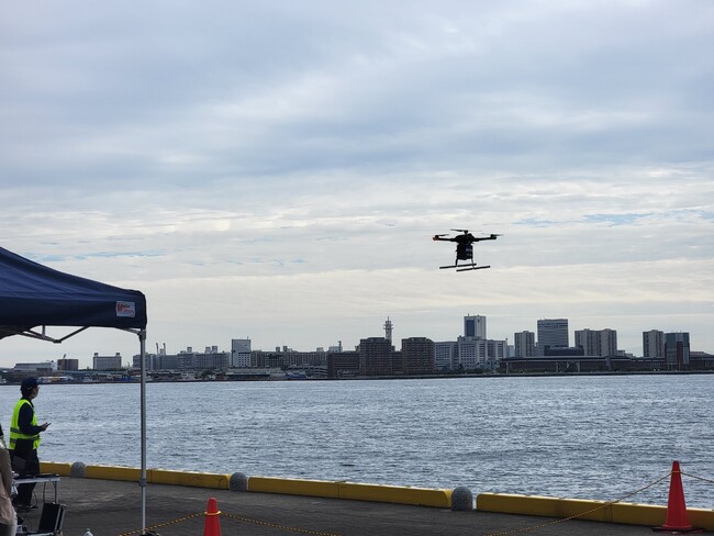 商品が入ったドローンが神戸港をわたってポートアイランドへ