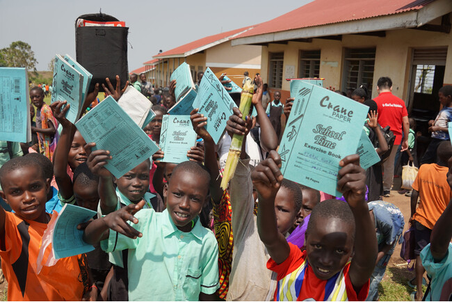 もらったばかりの新しいノートを掲げて見せるングルウエ初等教育校の子どもたち＝2024年2月19日撮影