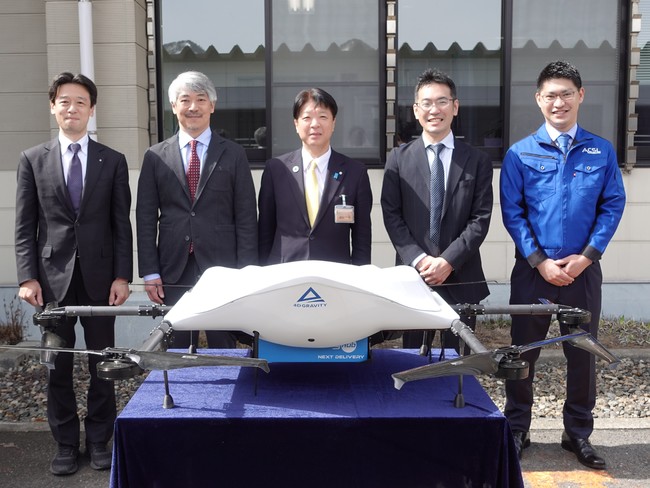 物流専用ドローンを前に写真右から、ACSL 代表取締役社長 兼 COO鷲谷聡之、KDDI (事業創造本部 ビジネス開発部 ドローン事業推進Gリーダー)博野 雅文、阿賀町長 神田一秋、エアロネクスト代表取締役CEO/NEXT DELIVERY代表取締役 田路 物流専用ドローンを前に写真右から、ACSL 代表取締役社長 兼 COO鷲谷聡之、KDDI (事業創造本部 ビジネス開発部 ドローン事業推進Gリーダー)博野 雅文、阿賀町長 神田一秋、エアロネクスト代表取締役CEO/NEXT DELIVERY代表取締役 田路