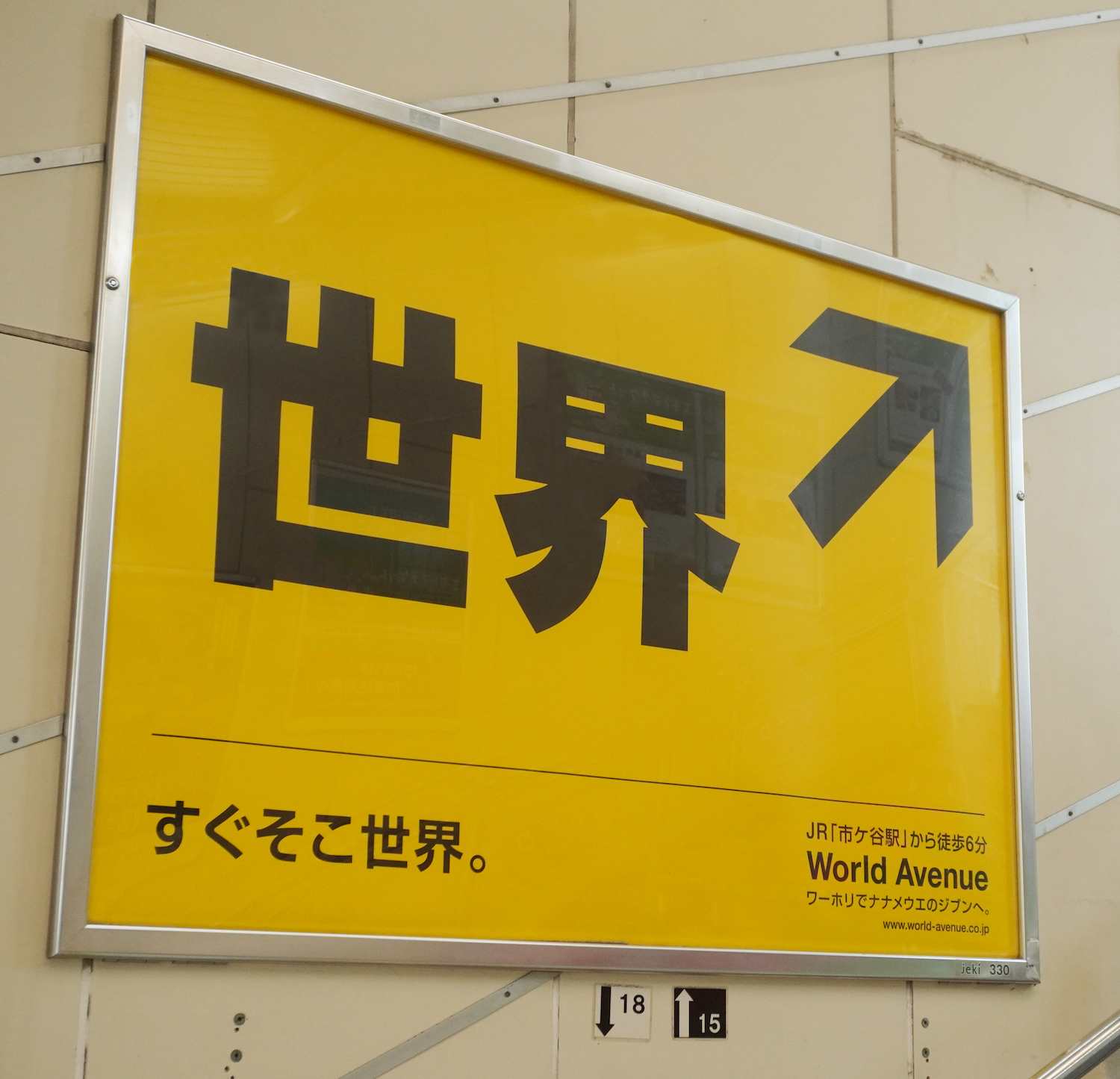 「世界」へ導くナゾの案内サインをJR市ケ谷駅に掲出しました。